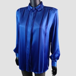 May include: A long-sleeved blue blouse with vertical stripes in varying shades of blue. The blouse has a collared neckline, buttoned cuffs, and a silky, shiny texture. The garment is displayed on a mannequin.