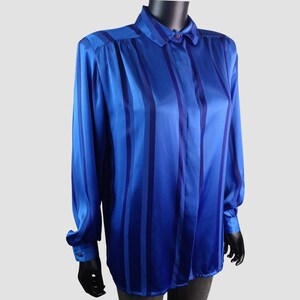 May include: A blue satin button-down shirt with vertical stripes in varying shades of blue. The long-sleeved shirt has a collared neckline and buttoned cuffs. The shirt is displayed on a mannequin.