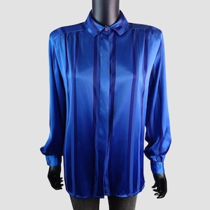 May include: A long-sleeved blue shirt with vertical stripes in varying shades of blue. The shirt has a classic collar and buttoned cuffs. The fabric appears to be a shiny satin or silk.
