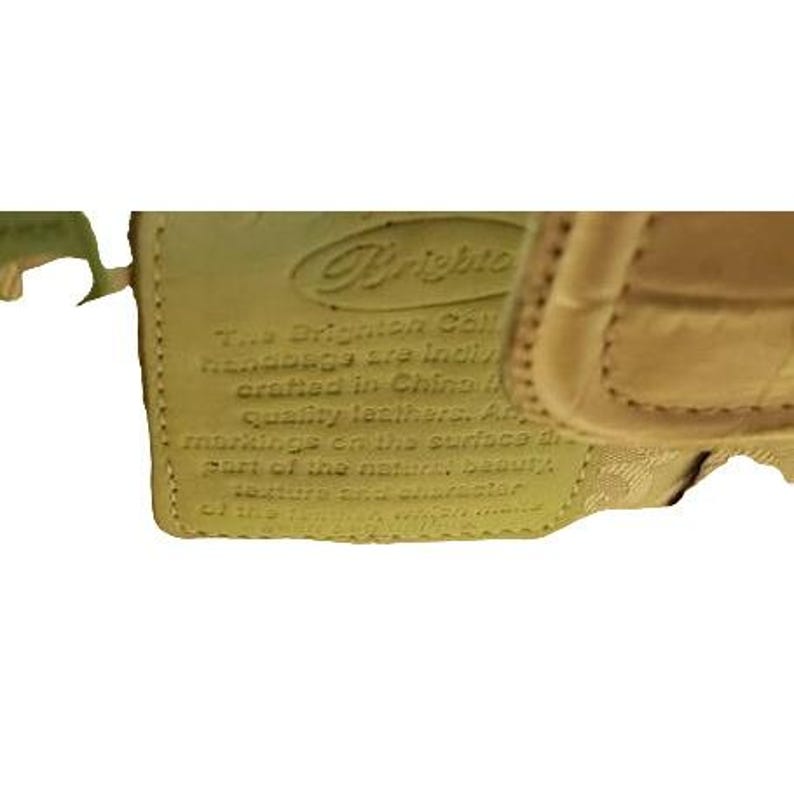May include: Close-up of a tan leather handbag tag with the text "The Brighton Collection handbags are individually crafted in China using quality leathers. All markings on the surface are part of the natural beauty of the  leather, and reflect the  handcrafted nature of this  Brighton Collection bag."