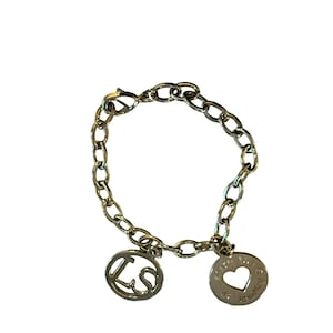 May include: A silver-toned bracelet with a chain link design. The bracelet features two charms: one with the letters "LS" and another with a heart-shaped cutout and the words "Love Jewelry". The bracelet is on a white background.
