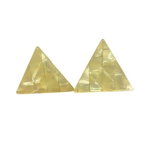 May include: A pair of triangular earrings made of light beige mother of pearl. The earrings are made of small squares of mother of pearl that are arranged in a geometric pattern.
