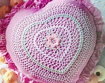 Peut inclure: Un coussin en forme de cœur rose avec une dentelle blanche au crochet et une fleur rose au crochet au centre.