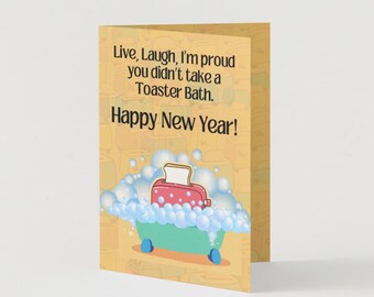May include: A yellow card with a cartoon illustration of a toaster in a bathtub with bubbles. The text on the card reads "Live, Laugh, I'm proud you didn't take a Toaster Bath. Happy New Year!"