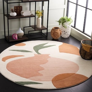 May include: A round, cream-colored rug with an abstract design featuring a large, peach-colored vase with green leaves and smaller orange and brown shapes.