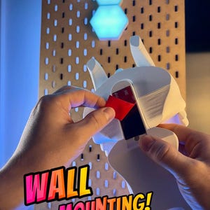 May include: A white 3D-printed wall mount is being prepared for installation. The mount is designed to hold hexagonal LED lights. The image includes the text "WALL MOUNTING!" and the logo for "3D FACTORY BOX".