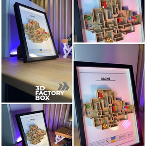 May include: A framed 3D map of the "Cache" level from a video game, with a black frame. The map is a detailed, multi-layered model with various colored zones and text labels. The frame is displayed on a wooden surface.