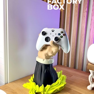 May include: A white Xbox controller held by a 3D-printed sculpture of a hand emerging from a black garment and a neon green base. The text "3D FACTORY BOX" is visible in the background.