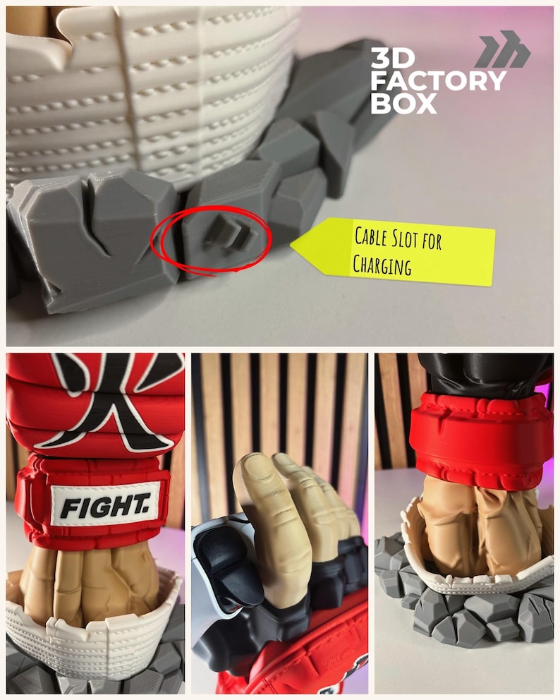 Puede incluir: Un soporte para mando impreso en 3D con un pu&ntilde;o estilizado que lleva un guante rojo con el texto FIGHT y un car&aacute;cter japon&eacute;s. La base tiene forma de rocas grises e incluye una ranura para el cable de carga del mando.