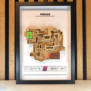 May include: A framed map of the Mirage map from the video game Counter-Strike: Global Offensive. The map is printed on a beige background with brown and green accents. The frame is black and the title "MIRAGE" is printed in black at the top of the map.