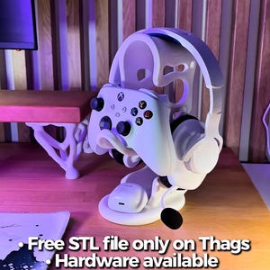 Peut inclure: Support blanc pour casque et manette de jeu. Le support maintient une manette Xbox blanche et un casque blanc et gris. Le support est sur une surface en bois. Le texte sur l'image dit "Free STL file only on Thags Hardware available on my Etsy".