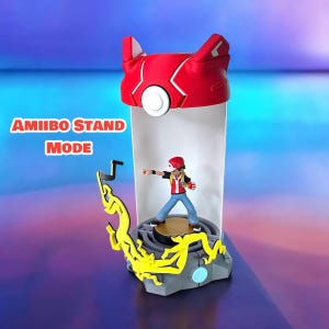May include: A red and white Pokemon Amiibo stand in "Amiibo Stand Mode" with a figure of a Pokemon trainer inside. The stand has a yellow lightning bolt design on the base.