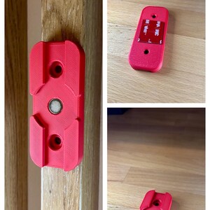 May include: Red 3D-printed mounting bracket with a magnetic center and two screw holes. The bracket is shown attached to a wooden surface and also separately. The text "3D FACTORY BOX" is visible in the image.