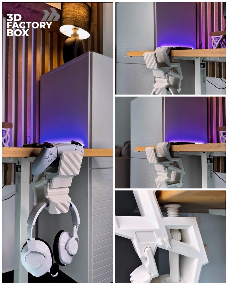 May include: A white 3D-printed desk mount for gaming accessories. The mount holds a white headset and a gray game controller. The text "3D FACTORY BOX" is visible in the upper left corner. The mount is attached to a wooden desk.