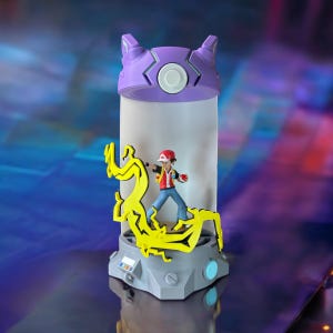 May include: A purple and gray Pokemon Poke Ball lamp with a yellow lightning bolt design and a figure of a Pokemon trainer inside.
