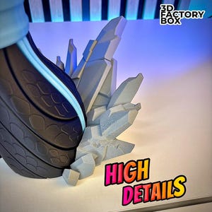 May include: A close-up of a 3D-printed sculpture with high detail. The sculpture features a dark gray, textured section with a light blue accent, and a light gray, crystalline structure. The words "HIGH DETAILS" are in a colorful, outlined font.