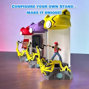 May include: Three different colored stands with a yellow, purple, and red top. Each stand has a different Pokemon character on it. The yellow stand has a figure of a trainer with a red hat and a red shirt. The stand has a yellow lightning bolt design. The text "CONFIGURE YOUR OWN STAND - MAKE IT UNIQUE!" is at the top of the image.