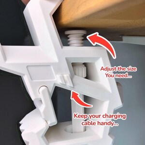 May include: White 3D Factory Box desk clamp with adjustable size and cable management. The clamp is being attached to a wooden surface. Text on the image reads: "Adjust the size you need..." and "Keep your charging cable handy..."