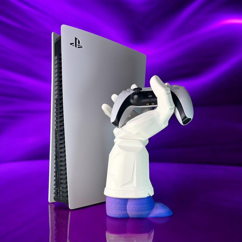 Puede incluir: Una consola PlayStation 5 blanca con un logotipo de PlayStation negro se encuentra junto a una mano blanca que sostiene un mando de PlayStation 5 negro. El fondo es un degradado morado.