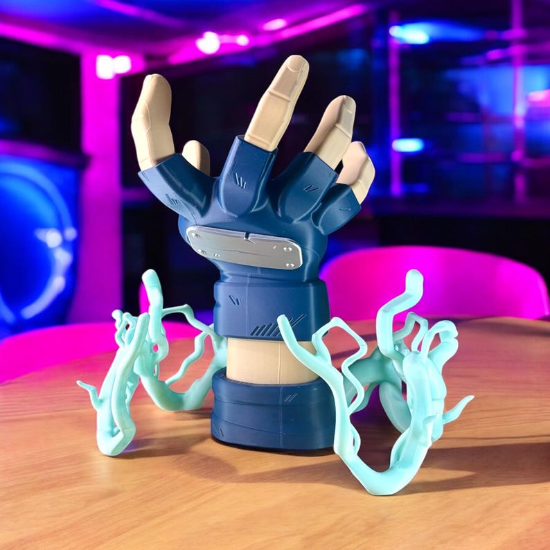 May include: A blue and tan hand-shaped figurine with outstretched fingers, a silver emblem, and light blue energy effects. The figurine is on a wooden surface with a blurred background of pink and blue lights.