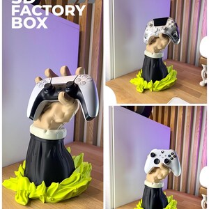Op de afbeelding: Een 3D-geprinte sculptuur van een hand die een videogamecontroller vasthoudt. De hand is bevestigd aan een zwarte basis met een witte kraag, omgeven door een heldergroen, bladerachtig ontwerp. De tekst "3D FACTORY BOX" staat in de linkerbovenhoek.