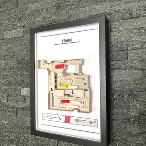 May include: A framed print of a train station layout with the word "TRAIN" at the top. The layout is in shades of beige, red, and yellow. The print is in a black frame.
