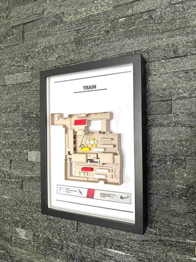 May include: A framed print of a train station layout with the word "TRAIN" at the top. The layout is in shades of beige, red, and yellow. The print is in a black frame.
