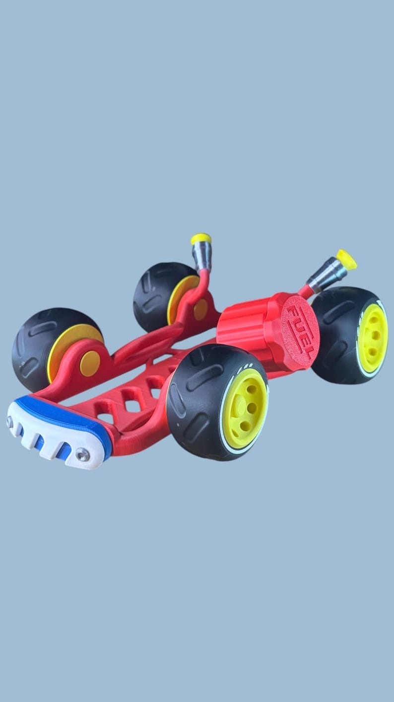 K&ouml;nnte beinhalten: Ein rotes und schwarzes Spielzeugauto mit gelben Akzenten. Das Auto hat vier schwarze R&auml;der mit gelben Felgen, ein rotes Fahrgestell und einen roten Tankdeckel. Die Vorderseite hat ein blaues, wei&szlig;es und rotes Design.