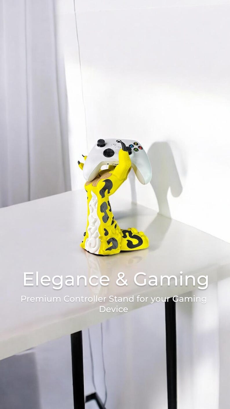 K&ouml;nnte beinhalten: Ein gelber und schwarzer, handf&ouml;rmiger Controller-St&auml;nder mit einem wei&szlig;en Videospiel-Controller, der in der Hand ruht. Der St&auml;nder steht auf einem wei&szlig;en Tisch mit einem schwarzen Metallbein. Der Text "Elegance & Gaming" befindet sich unter dem St&auml;nder, und der Text "Premium Controller Stand for your Gaming Device" befindet sich darunter.