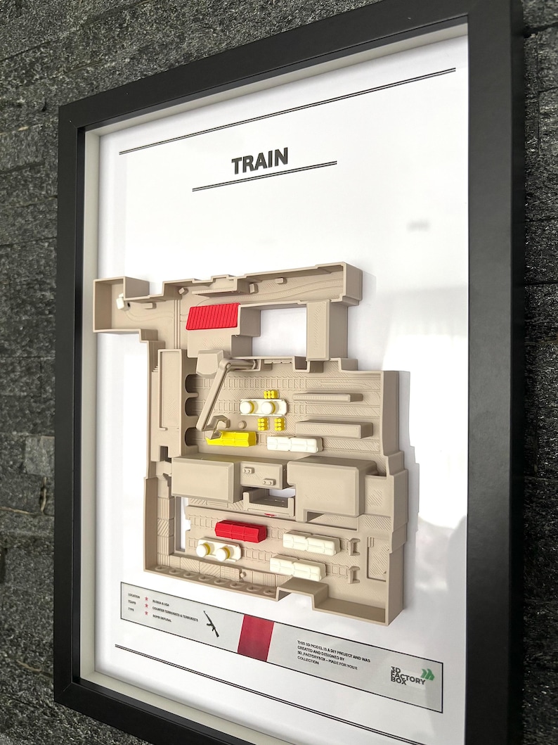 May include: A 3D printed map of the "Train" level from the video game "Counter-Strike: Global Offensive". The map is framed and features a beige color scheme with red and yellow accents. The map is labeled "TRAIN" at the top and includes the "The Factory Box" logo in the bottom right corner.