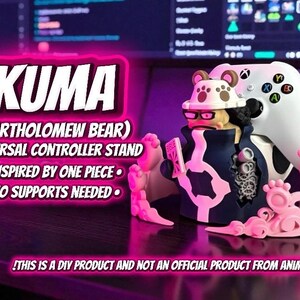 Puede incluir: Soporte universal para mando Kuma (Bartholomew Bear) rosa y azul marino. Inspirado en One Piece, presenta un dise&ntilde;o tem&aacute;tico de oso. Dise&ntilde;ado para sujetar un mando de juegos. El texto "KUMA" se muestra en blanco.