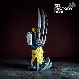 May include: A 3D printed sculpture of a blue and yellow gloved hand with three long, sharp, metallic silver claws extending upward. The glove features red blood-like splatters and is mounted on a gray, jagged, rock-like base. Text reads 3D FACTORY BOX.