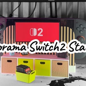May include: A diorama Switch 2 stand with a miniature entertainment center. The stand features a large screen with the number "2" on it, a small cabinet with drawers, and a neon green container holding game cartridges. The text "Diorama Switch 2 Stand" is displayed.