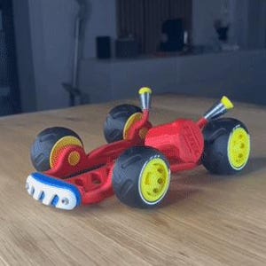 K&ouml;nnte beinhalten: Ein rotes Spielzeug-Rennauto mit schwarzen Reifen und gelben Felgen. Der vordere Sto&szlig;f&auml;nger ist wei&szlig; und blau. Das Auto hat gelbe Akzente und steht auf einer Holzoberfl&auml;che.