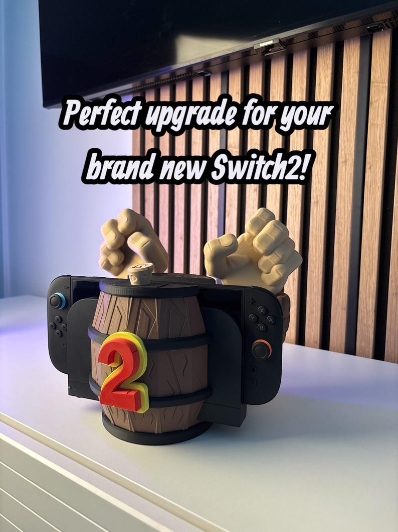May include: A black Nintendo Switch controller dock with a brown barrel design and the number 2 in red and yellow. The text reads "Perfect upgrade for your brand new Switch2!"