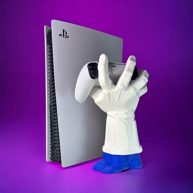 Puede incluir: Una consola PlayStation 5 blanca con una franja negra en el lateral. Una mano blanca sosteniendo un mando PlayStation 5 blanco est&aacute; de pie junto a la consola. El fondo es un degradado morado.