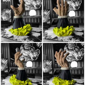 Op de afbeelding: Een 3D-geprinte sculptuur van een hand met een zwarte basis en een gele, stekelige accent. De hand heeft een lichtbruine kleur en de sculptuur heeft een gedetailleerd, getextureerd uiterlijk. De sculptuur is waarschijnlijk een decoratief item of een uniek kunstwerk.
