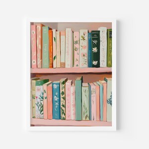 May include: A framed print of a bookshelf filled with colorful books. The books are in shades of pink, green, blue, and cream, with floral and botanical designs on the spines. The shelves are painted a soft pink.