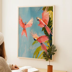K&ouml;nnte beinhalten: Ein Gem&auml;lde von drei rosa und gelben Aras, die vor einem blauen Himmel und gr&uuml;nen Palmenbl&auml;ttern fliegen.