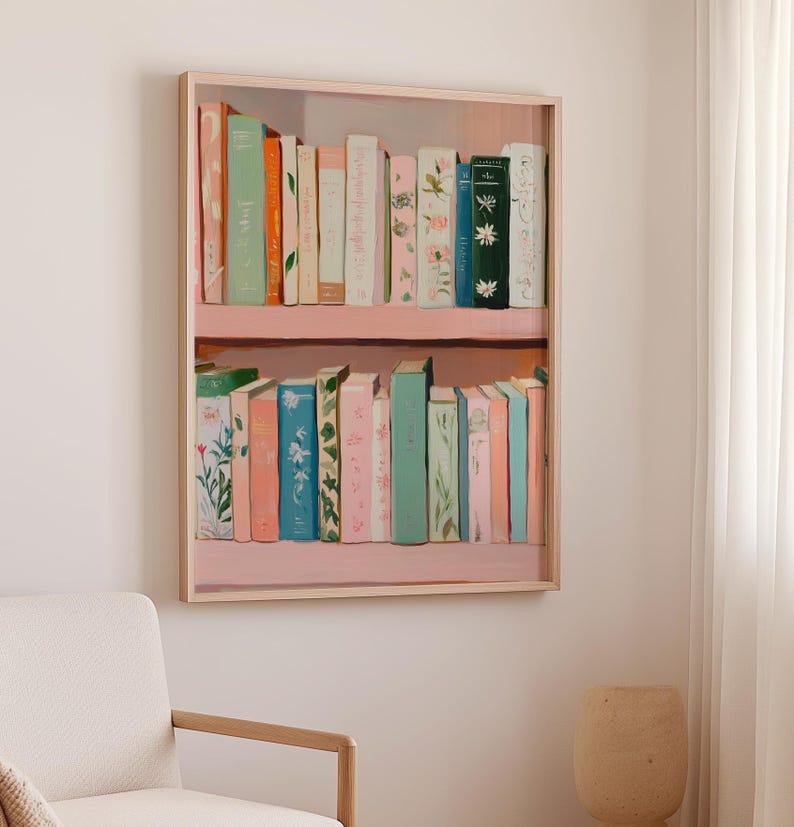 May include: A framed painting of a bookshelf filled with colorful books. The books are in shades of pink, green, blue, and orange, with floral and botanical designs. The bookshelf is painted pink and has a light wood frame.