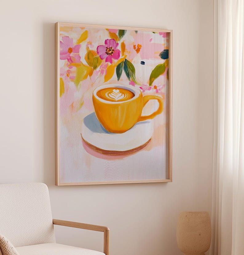 May include: A framed art print featuring a vibrant painting of a yellow coffee cup with latte art, resting on a white saucer. The background showcases a colorful floral design with pink, yellow, and green hues. The artwork is encased in a light-colored wooden frame.
