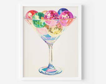 May include: A martini glass filled with colorful disco balls. The glass is clear and has a stem. The disco balls are various shades of pink, green, blue, and gold.