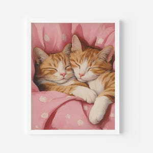 Op de afbeelding: Twee oranje tabby-katten knuffelen en slapen op een roze deken met witte stippen.
