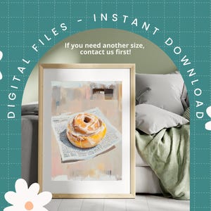 May include: A digital painting of a cinnamon roll with white icing on top of a newspaper. The painting is in a light brown frame and is hanging on a wall.
