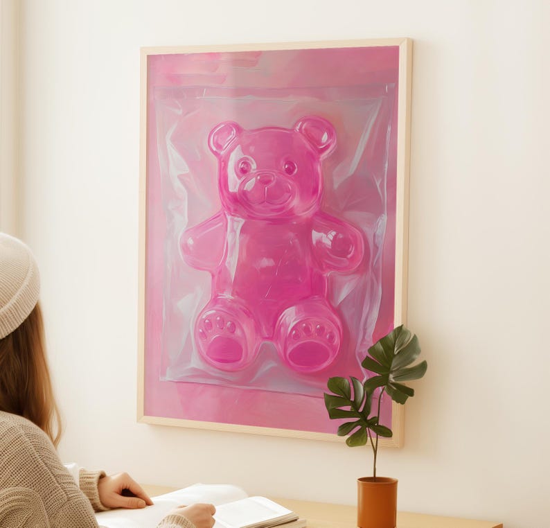 May include: A framed pink gummy bear sculpture in a clear plastic bag. The bear is in a pink frame with a white mount.
