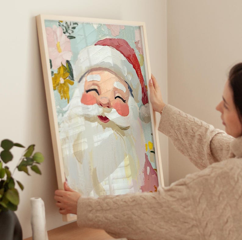 May include: A framed painting of Santa Claus with a white beard and red hat. The painting has a whimsical style with a floral background in shades of pink, yellow, and blue.