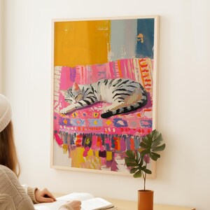 May include: A painting of a gray and white tabby cat sleeping on a colorful pink, yellow, and blue patterned rug.