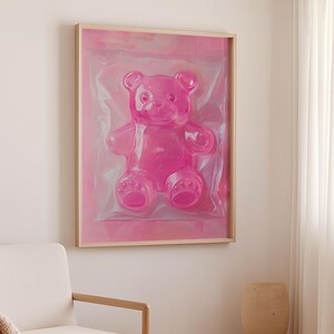 May include: A framed print of a pink gummy bear in a clear plastic bag. The bear is sitting up and has a friendly expression.