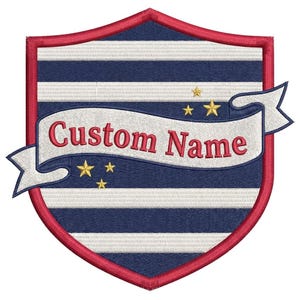 May include: An embroidered shield-shaped patch featuring horizontal navy blue and white stripes, a red border, and a white ribbon banner across the centre with the red text Custom Name. Five small gold stars are positioned above and below the banner.