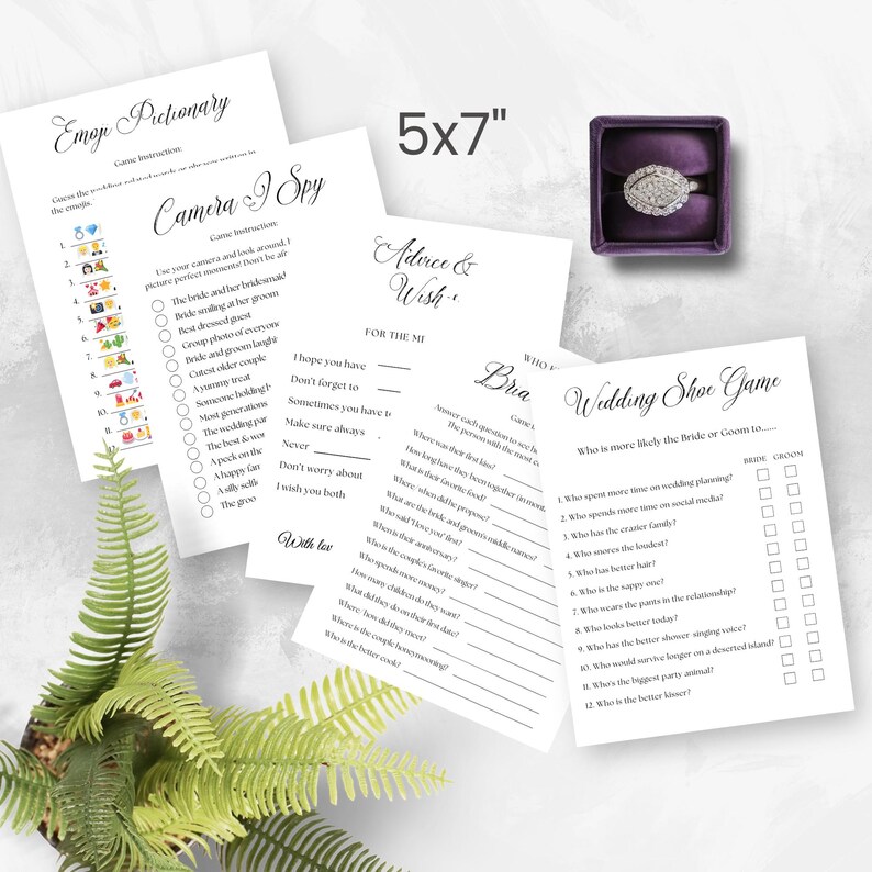 May include: A set of wedding games printed on five 5x7 inch white cards. The games include Emoji Pictionary, Camera I Spy, Advice & Wish, Bra, and Wedding Shoe Game. A diamond ring in a purple velvet box is also included.
